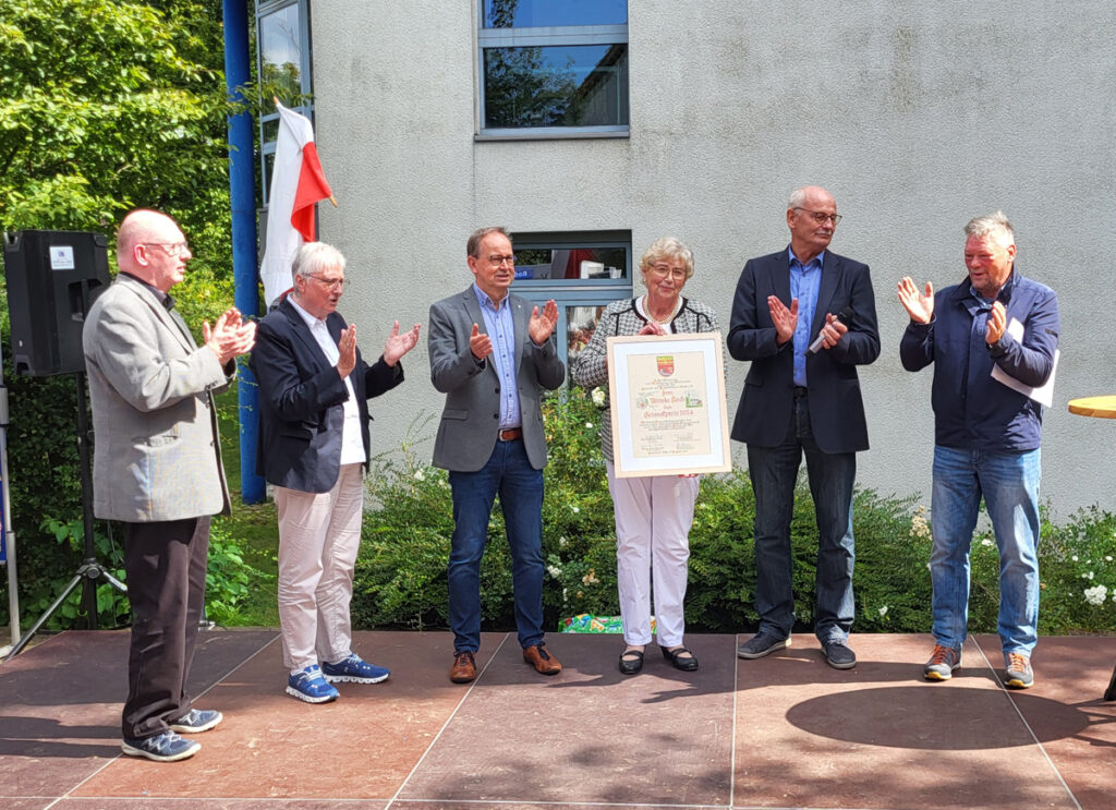 Die Jury um Dr. Michael Hardt (ehem. Pastor in Dahl), Marie-Luise Reineke (Ortsvorsteherin), Antonius Koch (Vorsitzender des Heimat- und Kulturvereins) sowie Jörg Neumann (Ortsheimatpfleger) applaudieren der neuen Preisträgerin. Die Volksbank OWL mit Herrn Grenz (3.v.l.) als Vertreter hat den Geldwert des Preises gestiftet.